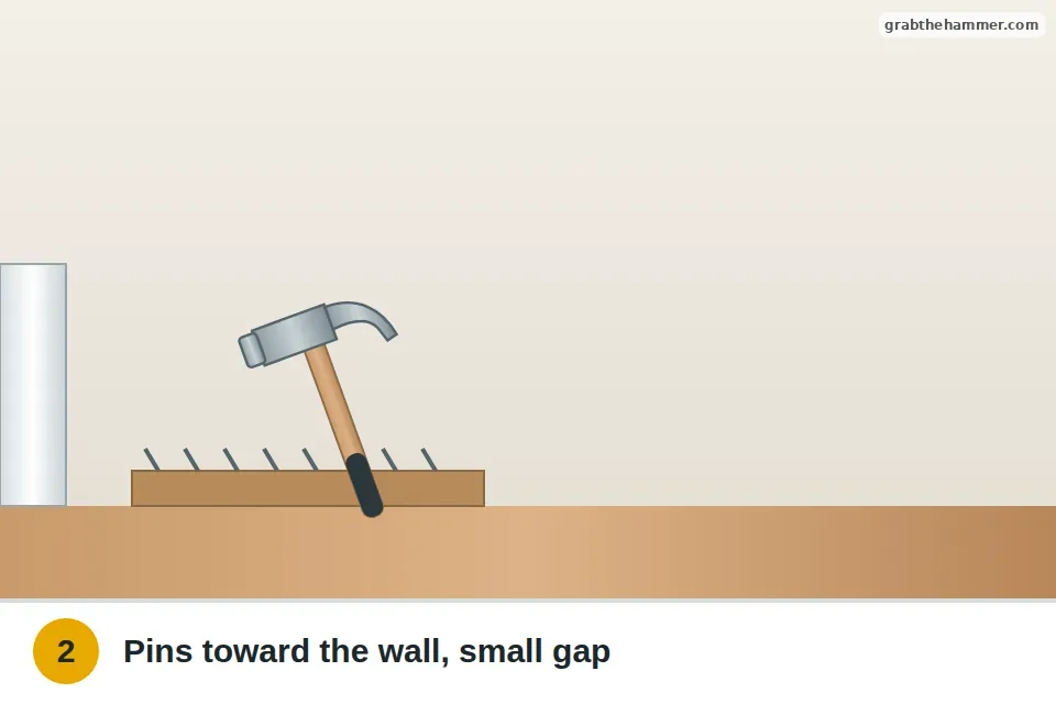 Hammer tapping a loose tack strip nail back into the floor, pins angled toward the wall