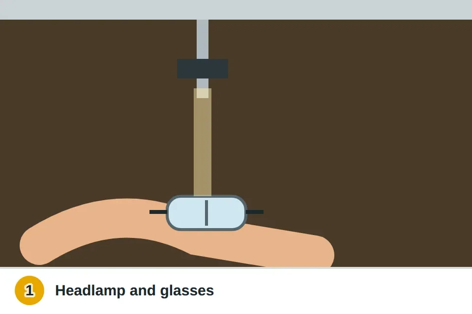 Person lying on their back in an emptied sink cabinet with a headlamp and safety glasses, looking up at the faucet mounting hardware