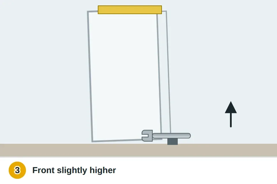 Level on top of a refrigerator and a wrench turning the front leveling leg up so the fridge tilts slightly back