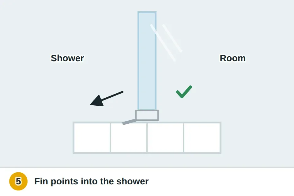 Side view of a new sweep on the bottom of the glass with its fin angled toward the inside of the shower, lightly touching the curb